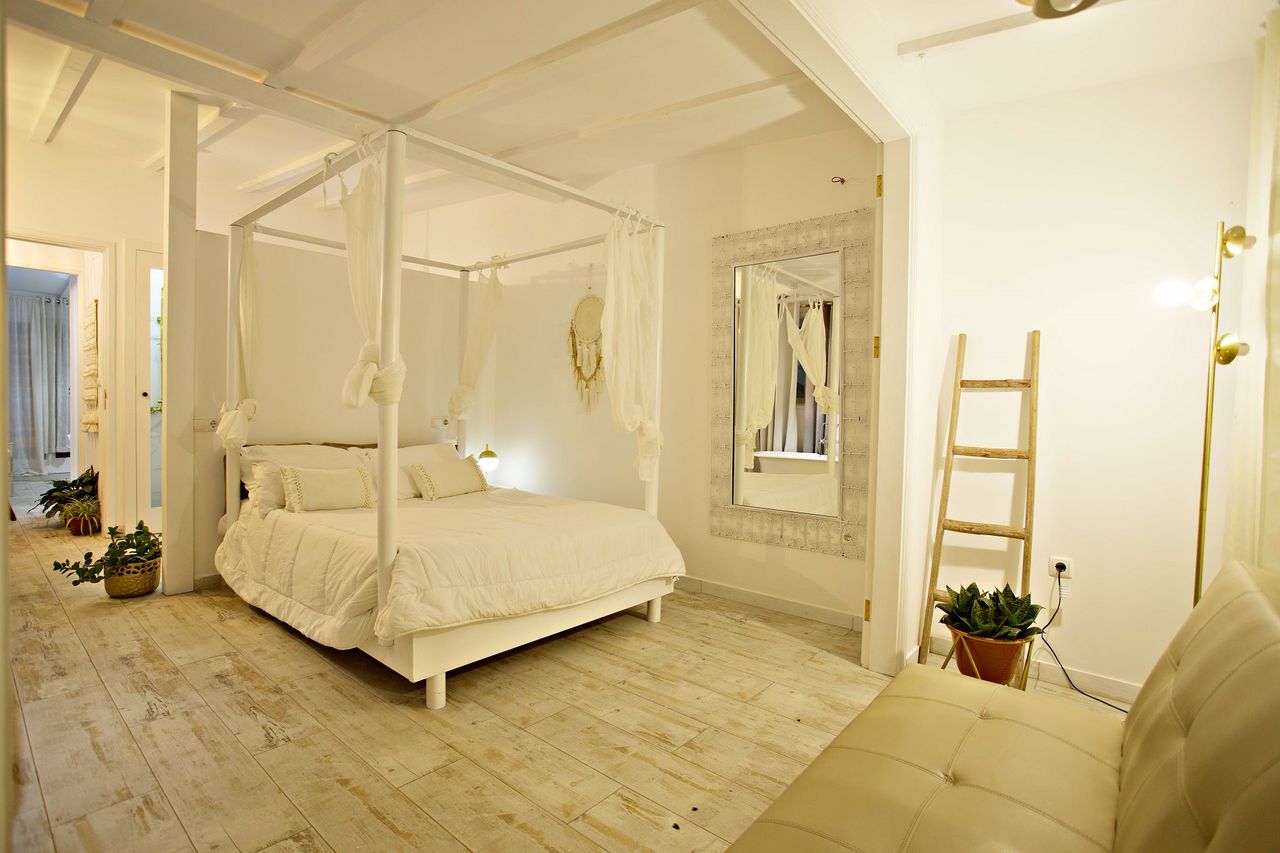 Quarto com cama de dossel branca, escada decorativa e espelho de moldura trabalhada