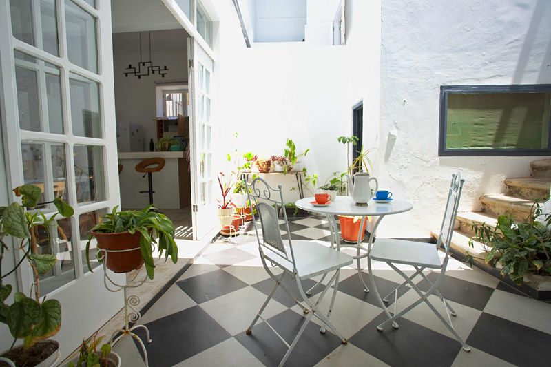 Pátio interior com mesa de café, plantas e chão axadrezado a preto e branco