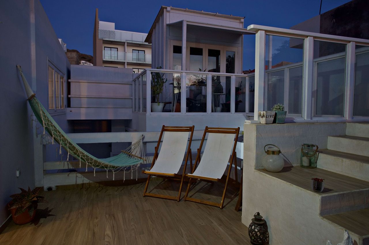 Terraço no topo da casa ao entardecer, com rede e cadeiras de lona