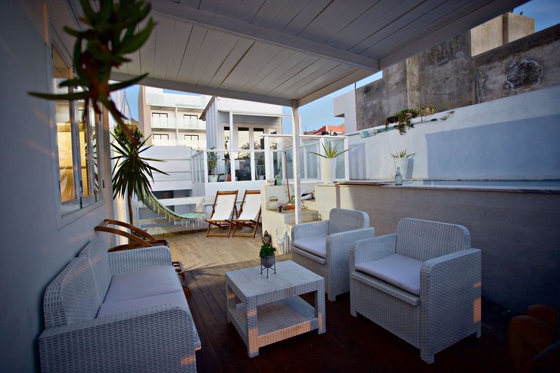 Zona coberta do terraço com sofás de vime e mesa de centro